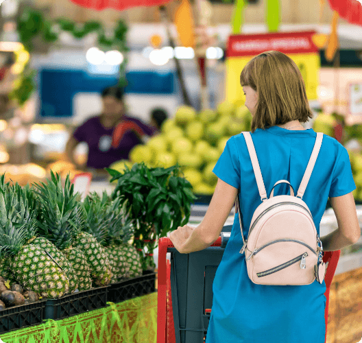 Young woman in fruit aisle with trolley.